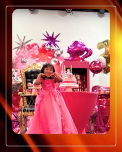 Smiling girl in a pink princess dress celebrating her birthday with cake and balloons at the best birthday party venue in Akron.