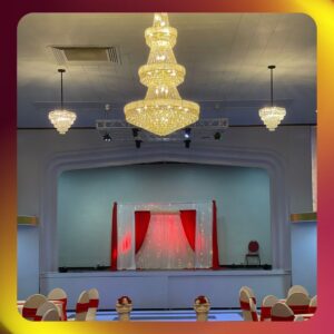 Beautifully decorated event hall at Royal Palace Akron Ohio with chandeliers, stage lights, and red-and-white wedding décor.