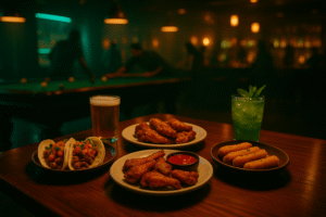 Plates of tacos, chicken wings, and mozzarella sticks with drinks at Royal Palace Lounge.