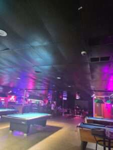 Interior of Royal Palace Lounge, a popular pool hall in Akron Ohio with multiple pool tables, neon lighting, and billiards players enjoying the nightlife atmosphere.