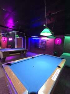 Pool table and neon-lit billiards area inside Royal Palace Akron’s best pool hall.