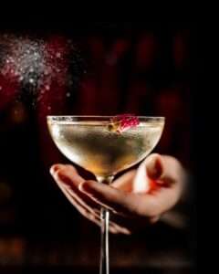 Close-up of a handcrafted cocktail garnished with flowers at Royal Palace Akron,cocktail bar served in a chilled coupe glass.”